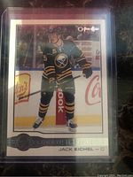Front of Jack Eichel rookie card showing player in Sabres uniform skating on ice in protective sleeve.