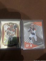 Two Joe Burrow rookie football cards side by side in plastic sleeves featuring Select Premier and Clear Vision series.