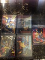 Five Wolverine-themed trading cards displayed together on a dark marble surface, showing artwork and variety of styles.