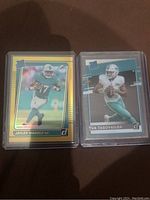 Front view of Jaylen Waddle gold press proof card next to Tua Tagovailoa prizm card in plastic sleeves.