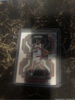 Front side of Scottie Barnes Prizm rookie card in plastic holder on dark surface showing player image and design details.