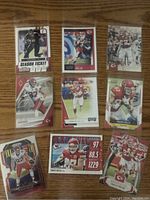 Photo showing nine Travis Kelce football cards of different brands and designs on a wooden surface.