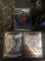 Three Tyrese Maxey rookie cards in protective sleeves: Select Prizm, Silver Prizm Crusade, and Draft Picks.
