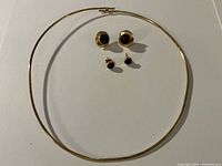 Overview of choker and both pairs of earrings laid flat