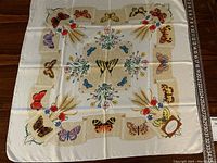 Full view of square silk scarf laid flat on wood floor