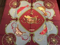 Full scarf laid flat showing burgundy and gray background with carriage wheel and spring motifs