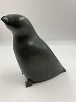 Side profile view of penguin sculpture showing overall shape and polished surface.