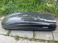 Front side view of closed black cargo box on driveway