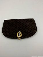 Front view of wallet showing brown suede exterior with tonal geometric ‘G’ pattern and mixed metal horseshoe clasp