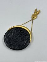 Front angle view of round alligator purse with gold-tone frame and attached belt clip