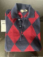 Folded navy and red argyle polo sweater, top view