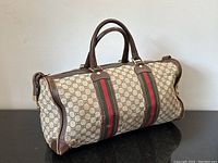 Side view showing beige GG monogram canvas, green/red web stripes, brown leather trim