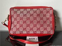 Front view of bag showing red leather trim and beige/red GG monogram fabric exterior