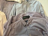 Several folded and hanging Ralph Lauren shirts in pinstripe and solid colors.