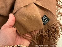 Close-up of embroidered 'Hermès' logo and woven label on corner