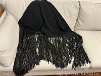 Full view of black triangular shawl draped to show shape and fringe