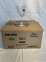 Wine glass standing on top of the original box with Capri Collection and model details.