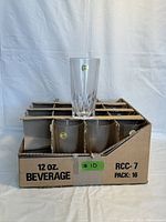 Eight of the vintage CAPRI lead crystal glasses shown packed in original cardboard holder, one glass placed on top showing clear crystal with gold branding sticker on front.
