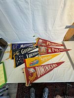 Full view of 7 vintage souvenir travel pennants featuring various U.S. states and one Caribbean destination.