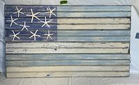 Full view of handcrafted folk art flag with distressed blue and white wood, accented with starfish in canton