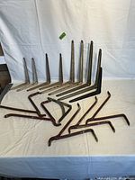 All 15 antique metal shelf brackets arranged in rows showing variety of sizes and colors including white, black, and brown rusty finish.