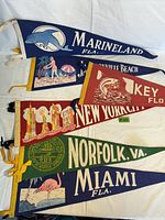 Photo showing all six travel pennants laid flat overlapping, featuring colorful vintage designs and city/state names.