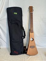 Full view of Martin Backpacker guitar with black soft carry case standing upright.