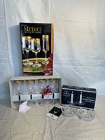 Full lot showing Medici crystal stemware box with four glasses inside, and Capri crystal candle holders box with two candle holders beside it.