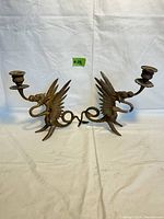Pair of antique brass griffin candlesticks placed side by side on a white background, showing overall design and size.