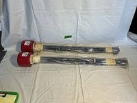 Two new old stock Chromalox immersion heaters laid flat with visible long heating elements wrapped in plastic and red electrical housing.