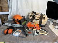 Overview of all items: chainsaw, helmet with visor, earmuffs, tool, parts kit, canvas bag