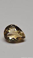 Close-up image of the pear-shaped faceted golden citrine gemstone showcasing the clarity and cut.