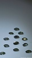 Loose marquis cut calibrated natural alexandrite gemstones displayed on a neutral surface, showing their greenish hues.