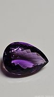 Pear-shaped deep purple amethyst gemstone displaying rich color and precise faceting.