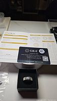 Men's moissanite diamond ring in black box with GRA card and certificate behind.