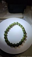 Photo showing the full circular stretch bracelet made of natural green jade beads, 8mm size beads, with light and dark green color.