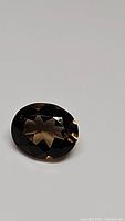 Oval cut natural smokey quartz gemstone showing faceted surface and internal brilliance.