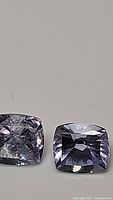 Close-up photo of two octagon cut Tanzanite gemstones with light purple color, showing facets and light reflections.