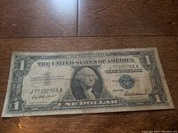 Front side of the 1957 silver certificate one dollar bill showing George Washington portrait and serial number J77337765A, with blue seal and signatures.