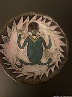 Top view of the wooden bowl showing the painted figure surrounded by pink and white angular shapes.