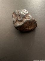 Close-up photo showing irregular meteorite with metallic and brown textured surface.
