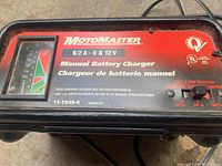 Close-up of front label showing MotoMaster branding, model info, amp selector and charge gauge.