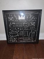 Full-frontal view of the framed Basquiat print leaning against wall