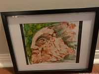Framed surreal painting showing cracked stone face with green background