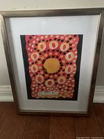 Photo of framed abstract painting with circular patterns in red, pink, white, and yellow colors, signed and dated by artist Nidhi Bandil Agarwal in 2022.
