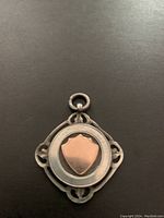 Full front view of the sterling silver pendant with rose gold shield on black background.
