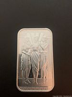 Front side of the silver bar showing detailed embossed artwork of three women and geometric border.