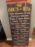 Full view of the three connected wooden panels with the ABC's of life inspirational text in multicolor letters on dark distressed wood.