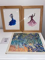Two framed watercolor paintings of dancers and an unframed Van Gogh Irises print on a white surface.