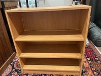 Front view of the wooden bookcase showing three shelves and a light wood grain finish.